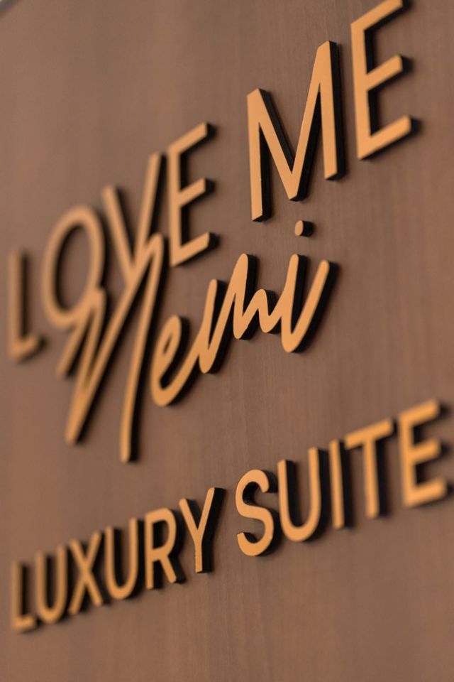 Logo Love Me Nemi in oro su parete di noce — Luxury Suite a Nemi