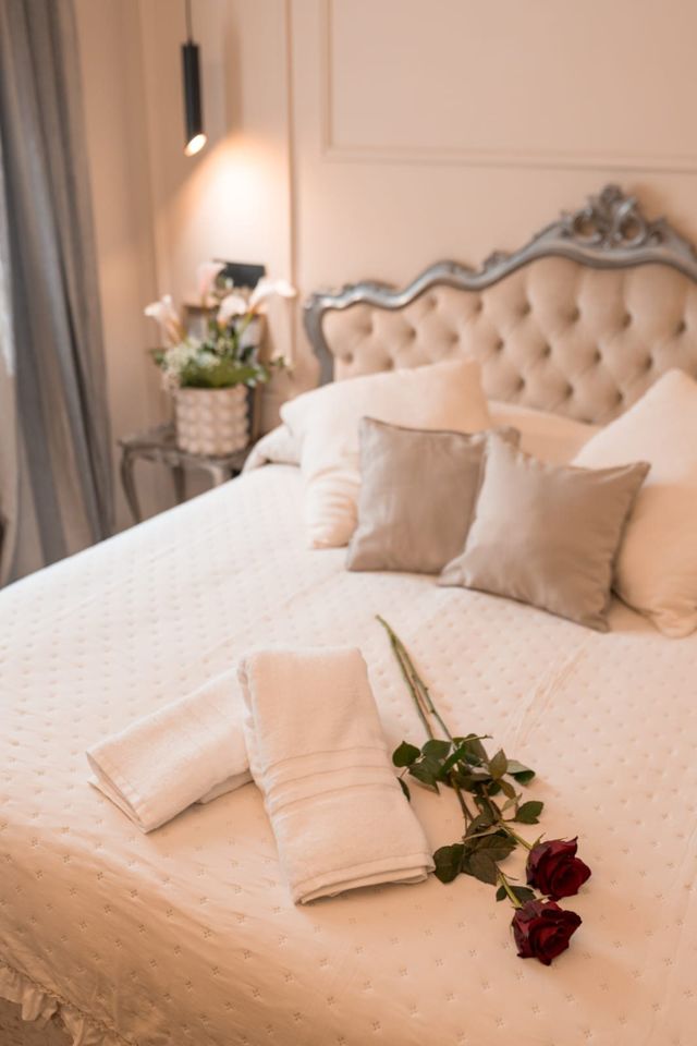Letto matrimoniale con testiera capitonné e rose rosse sul copriletto, Luxury Suite a Nemi
