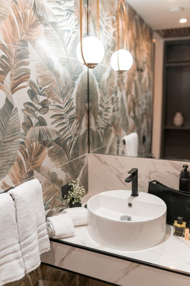 Bagno della suite con lavabo tondo, specchio e parete a foglie tropicali