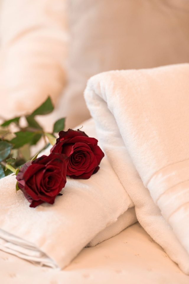 Due rose rosse posate sugli asciugamani piegati sul letto