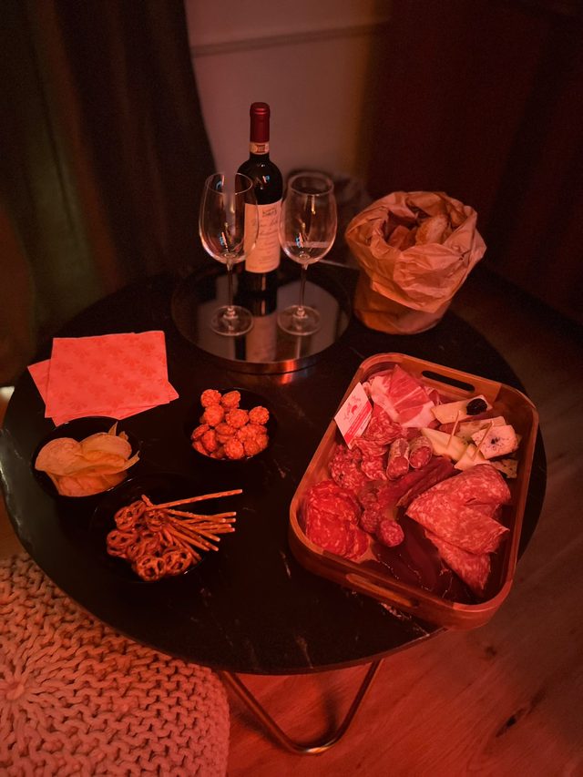 Tagliere di salumi e formaggi con vino rosso e due calici serviti in camera